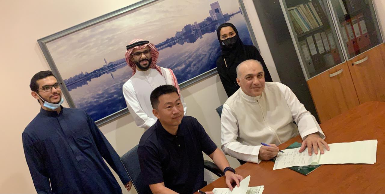 Mazin Kurdi signing an agreement with Andy, Director General of the Chinese company CGM, in an office.